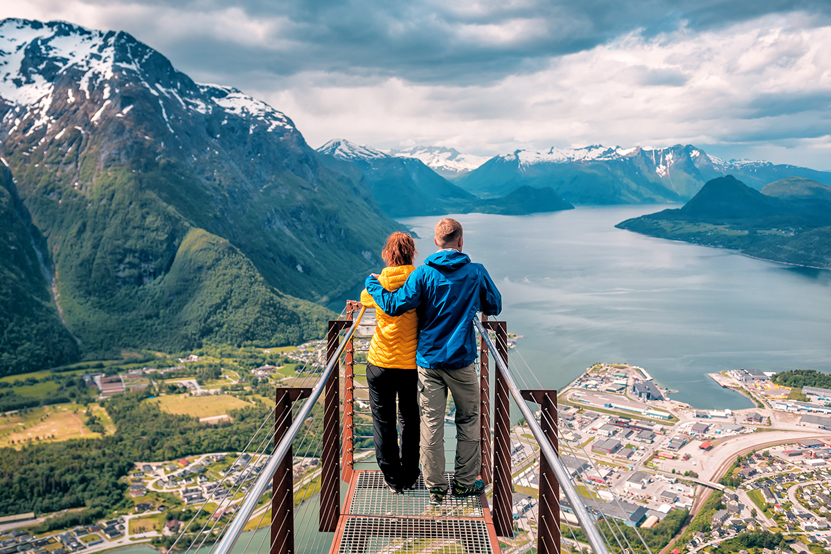happy blue yellow couple tourists stands on rampestreken in Norway